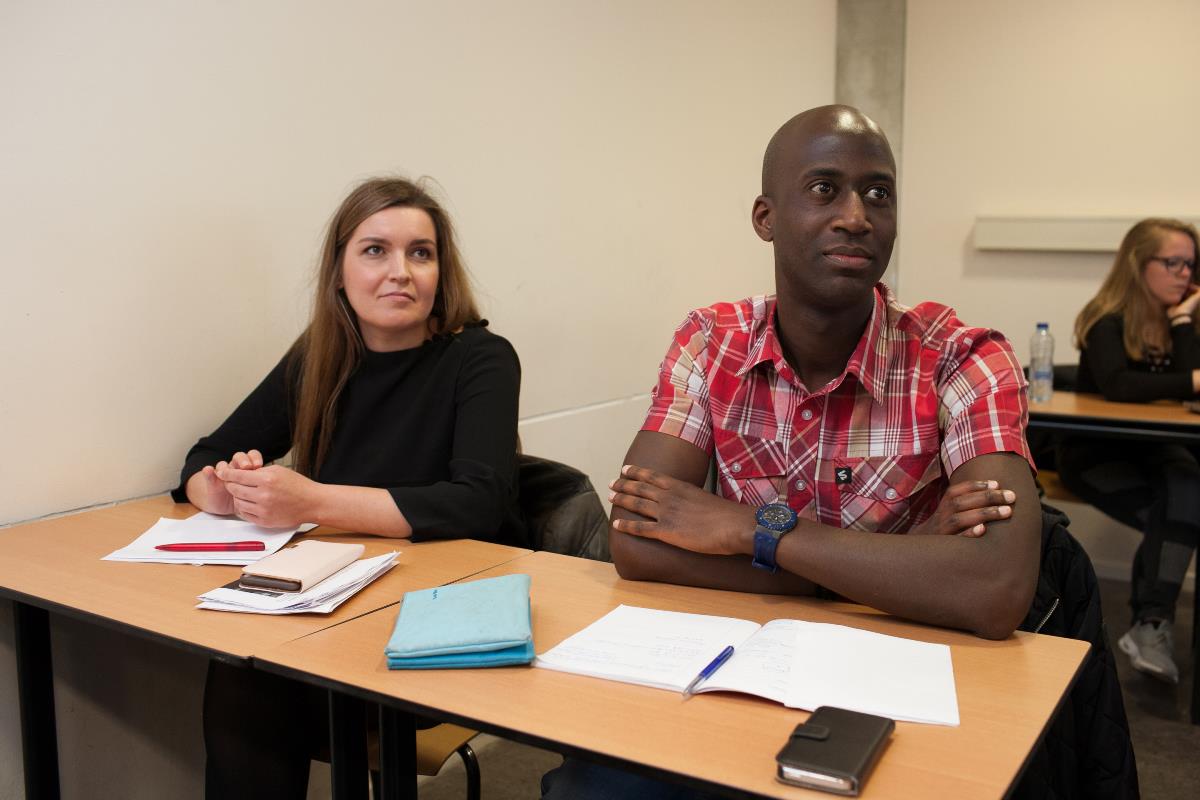 Twee studenten volgen les aan tafel