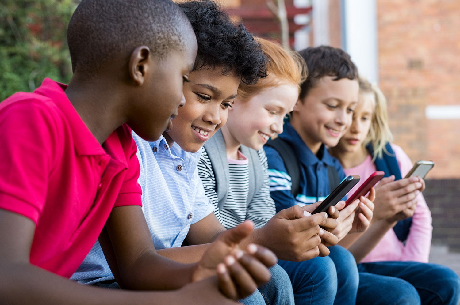 Groep kinderen zitten naast elkaar aan hun mobiel