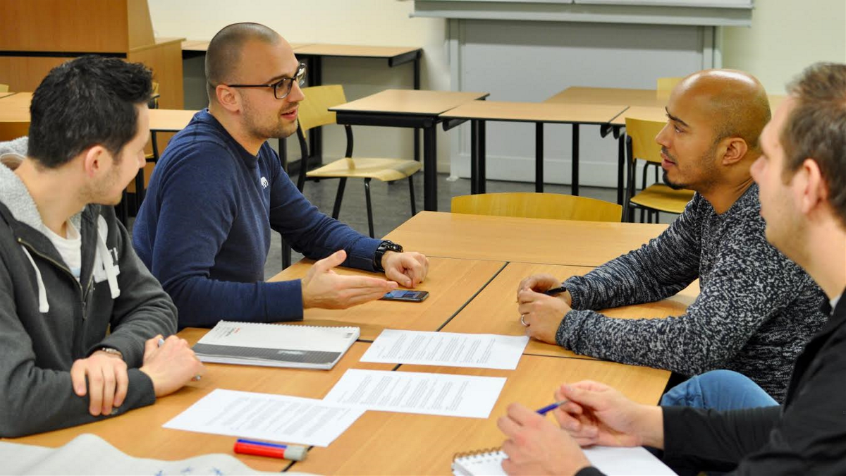 Vier personen hebben een bespreking aan tafel