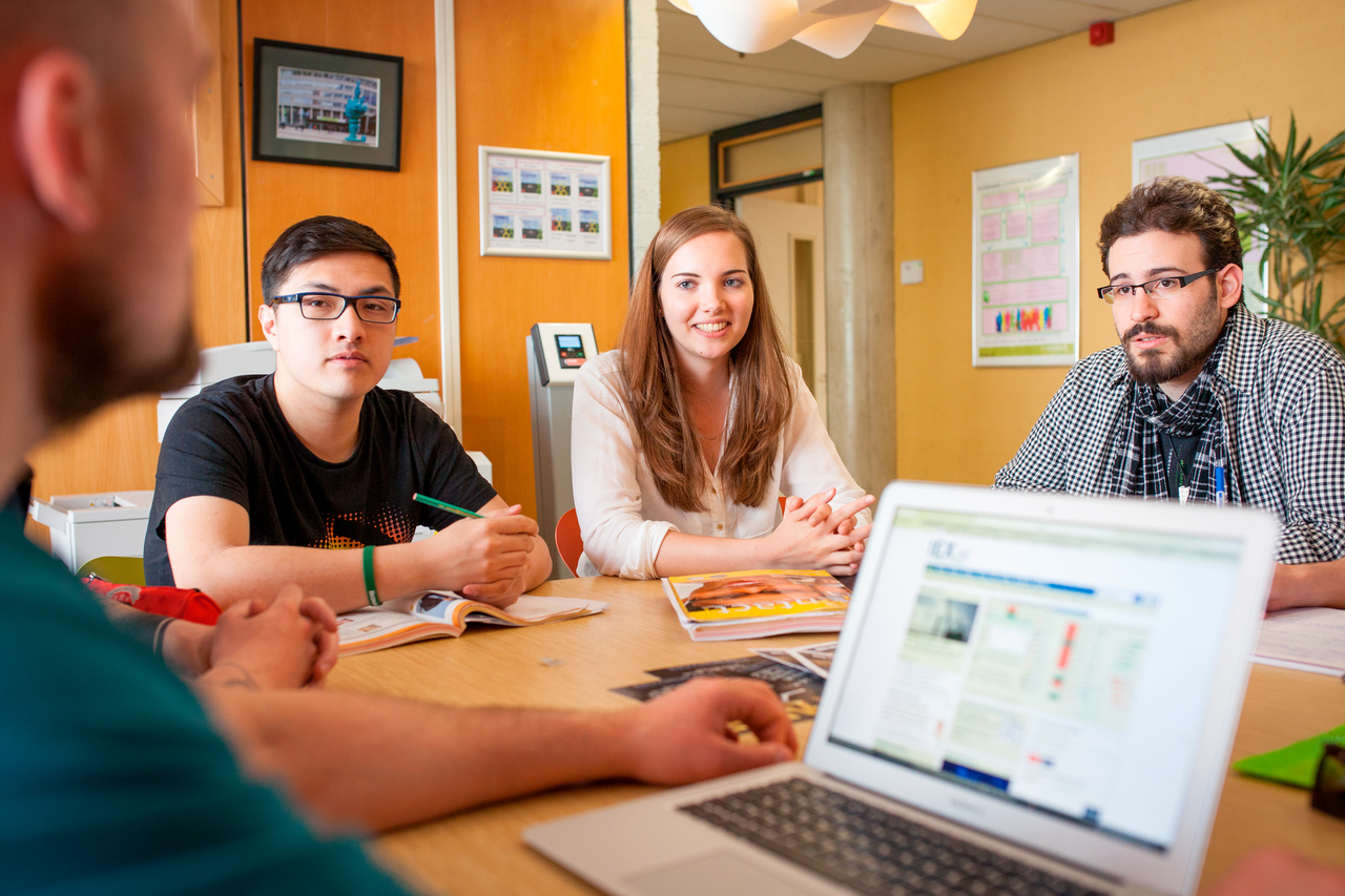 Vier studenten bespreken aan tafel met laptop