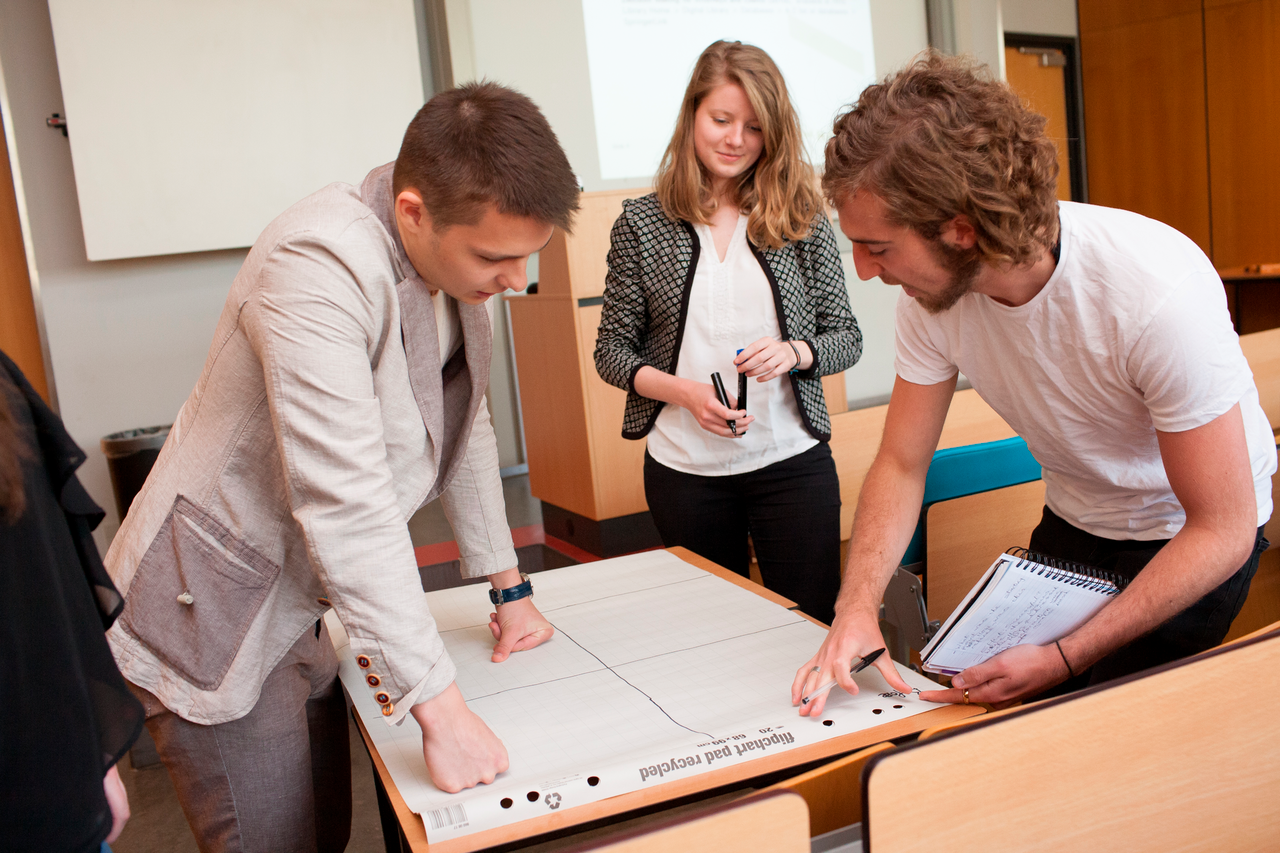 Drie studenten overleggen rondom tafel