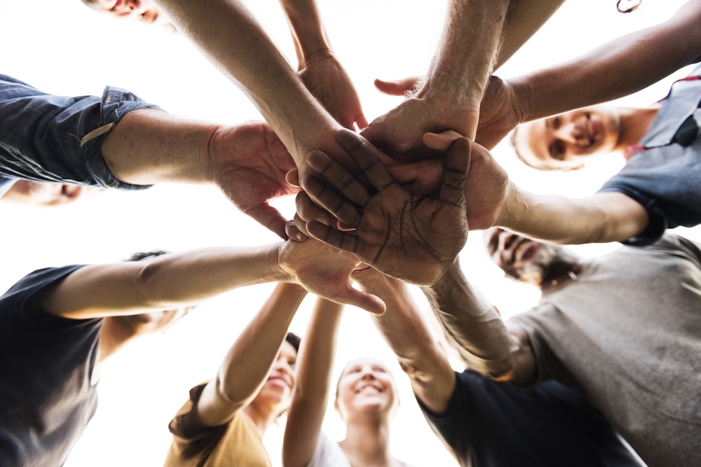 A group of people in a circle form with their hands above each other