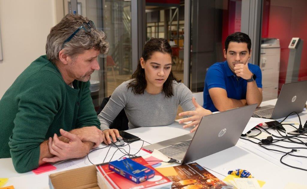 Docent helpt twee studenten