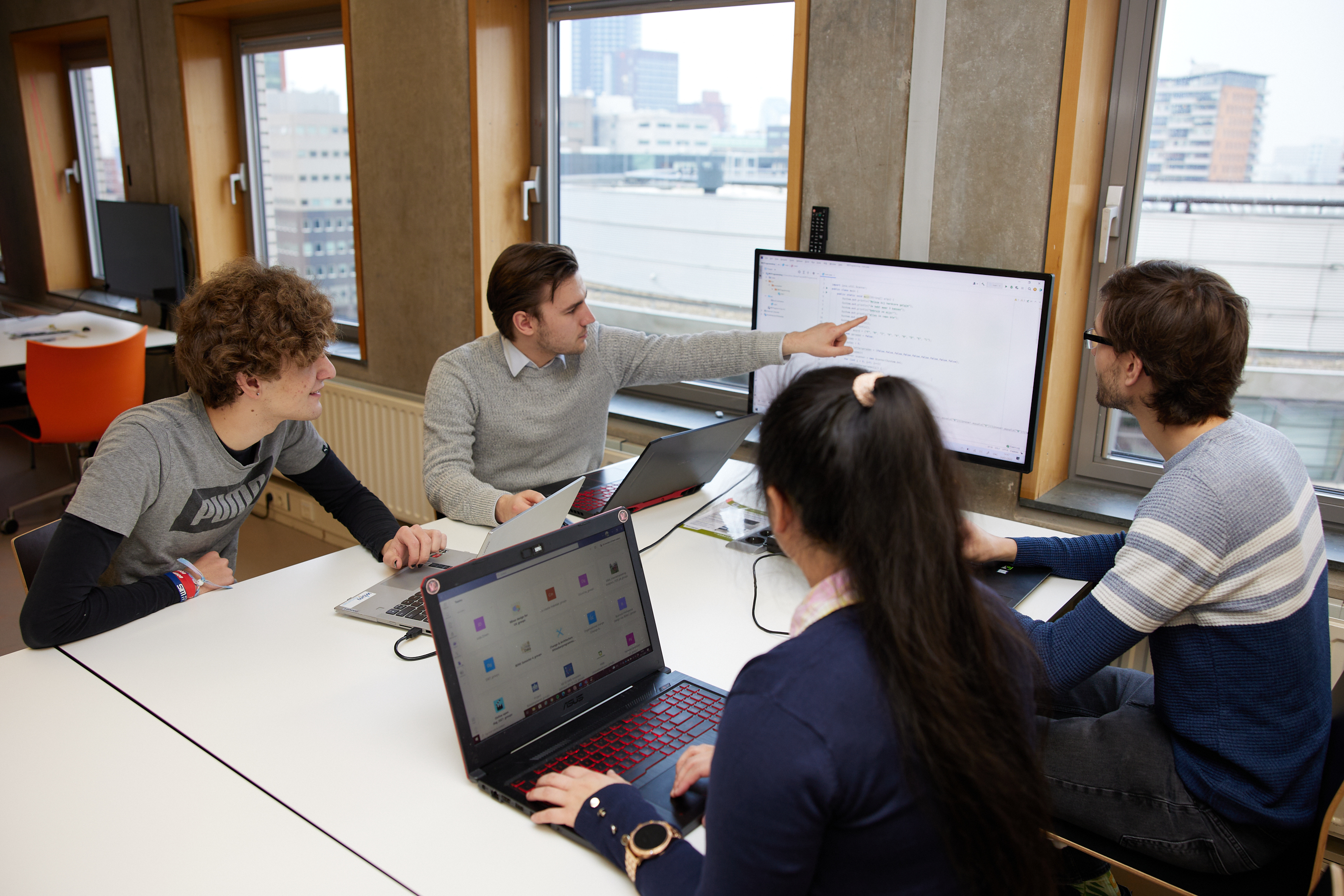 Vier studenten in overleg met laptops