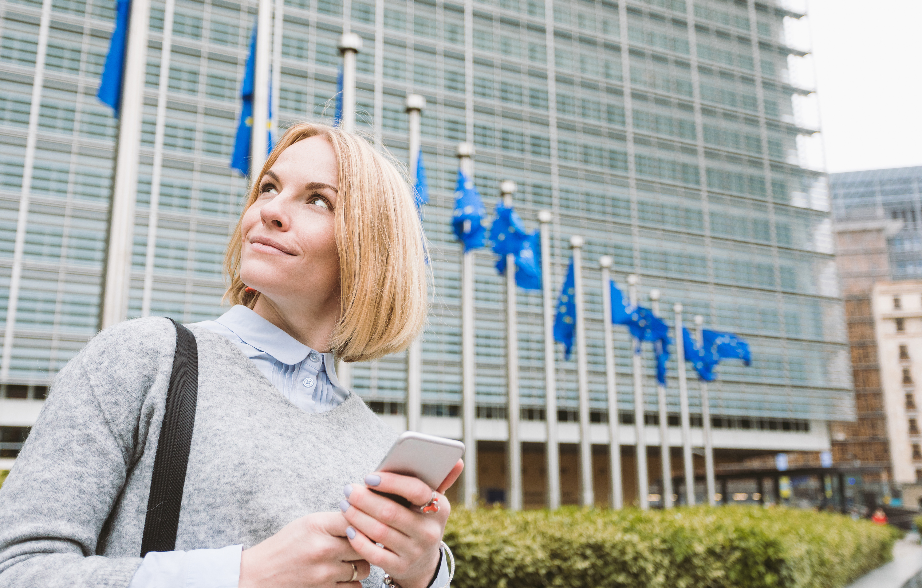 Lectoraat Changing Role of Europe, vrouw kijkt naar de vlaggen van de Europese Unie in Brussel