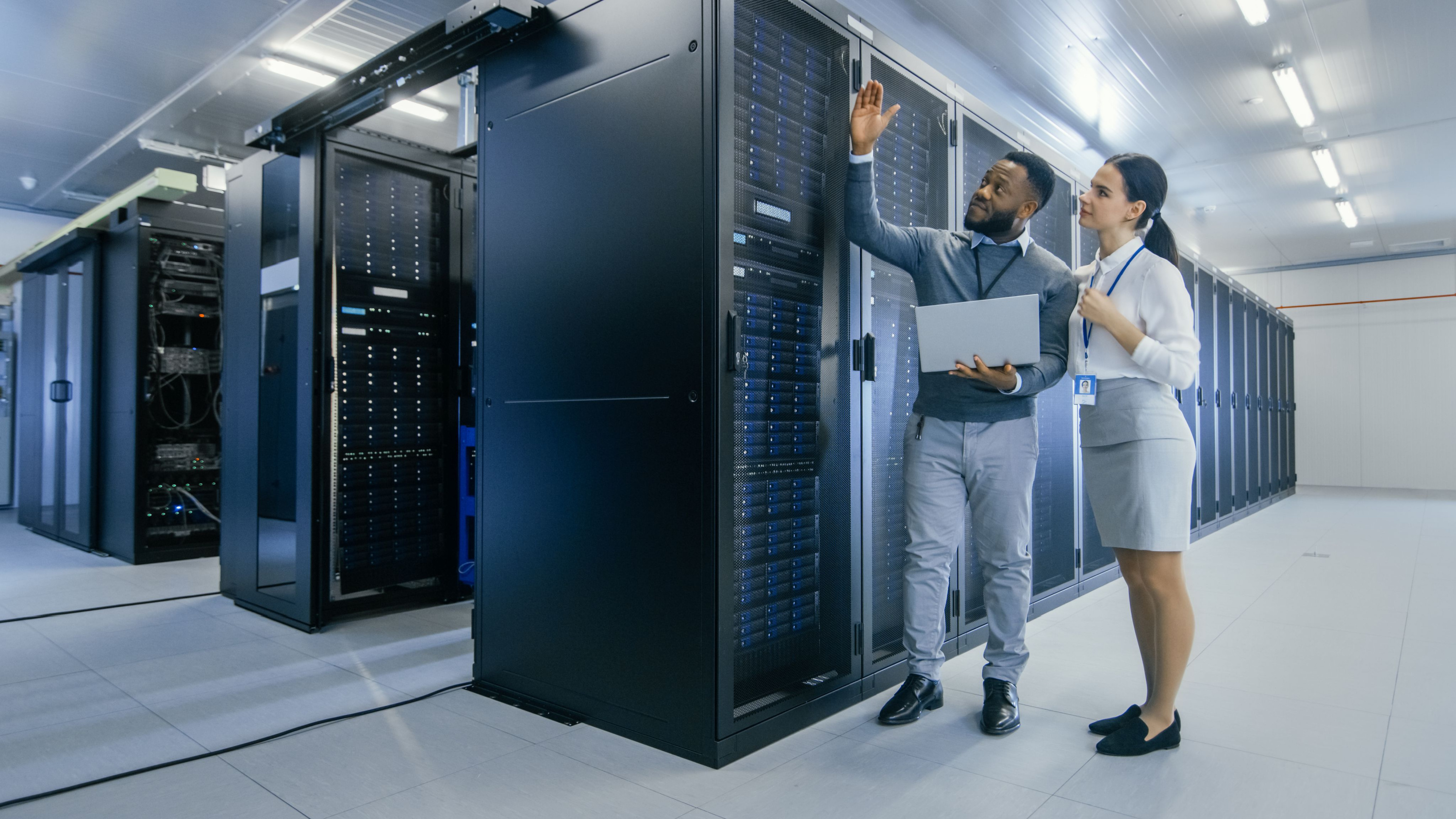 Lectoraat Networks and Systems Engineering, IT-ingenieur voert diagnose uit en spreekt met een vrouwelijke manager in het datacenter naast een serverrack