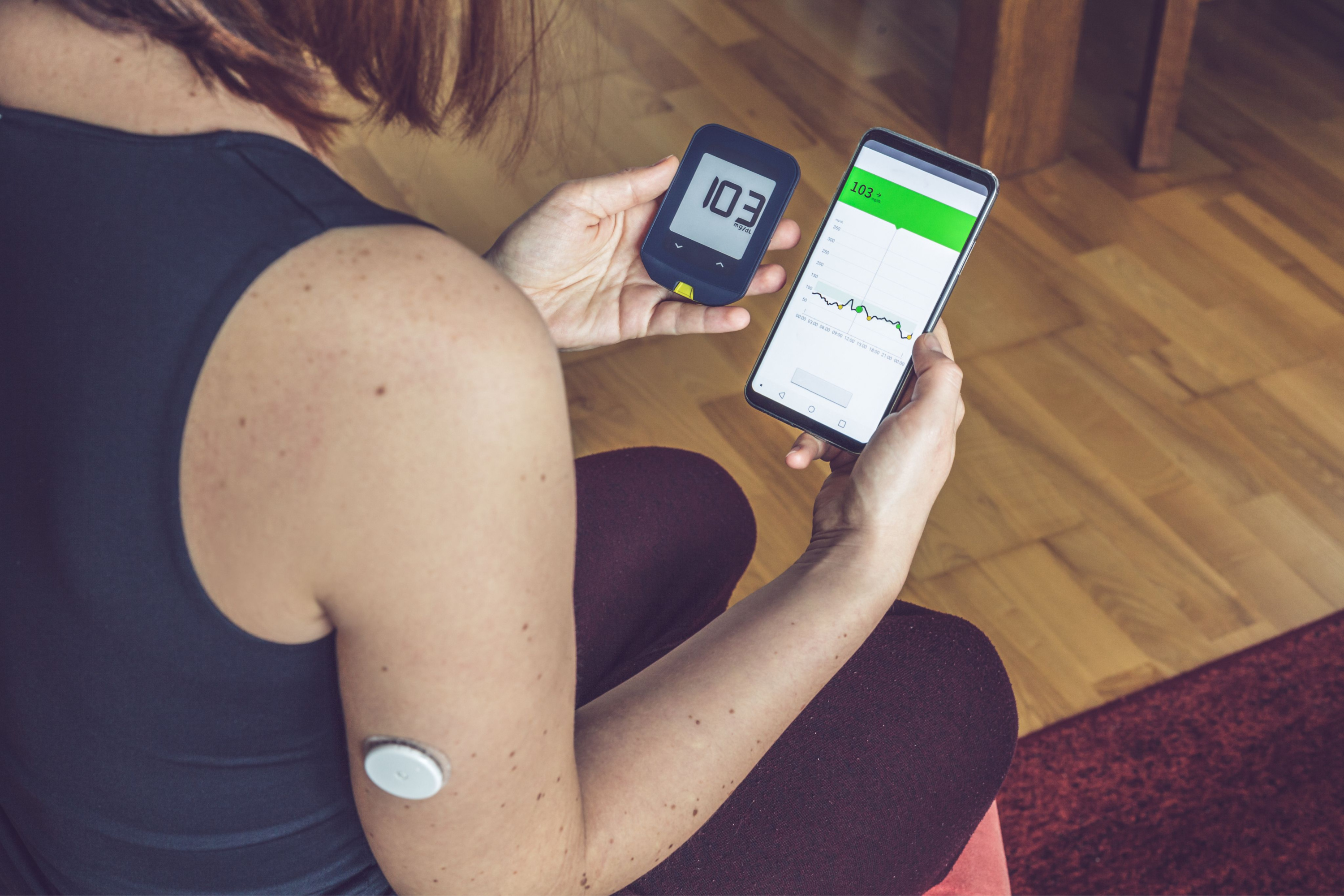 Sensor systems, Vrouw controleert de resultaten op de traditionele glucometer en de mobiele telefoon die van de externe sensor leest