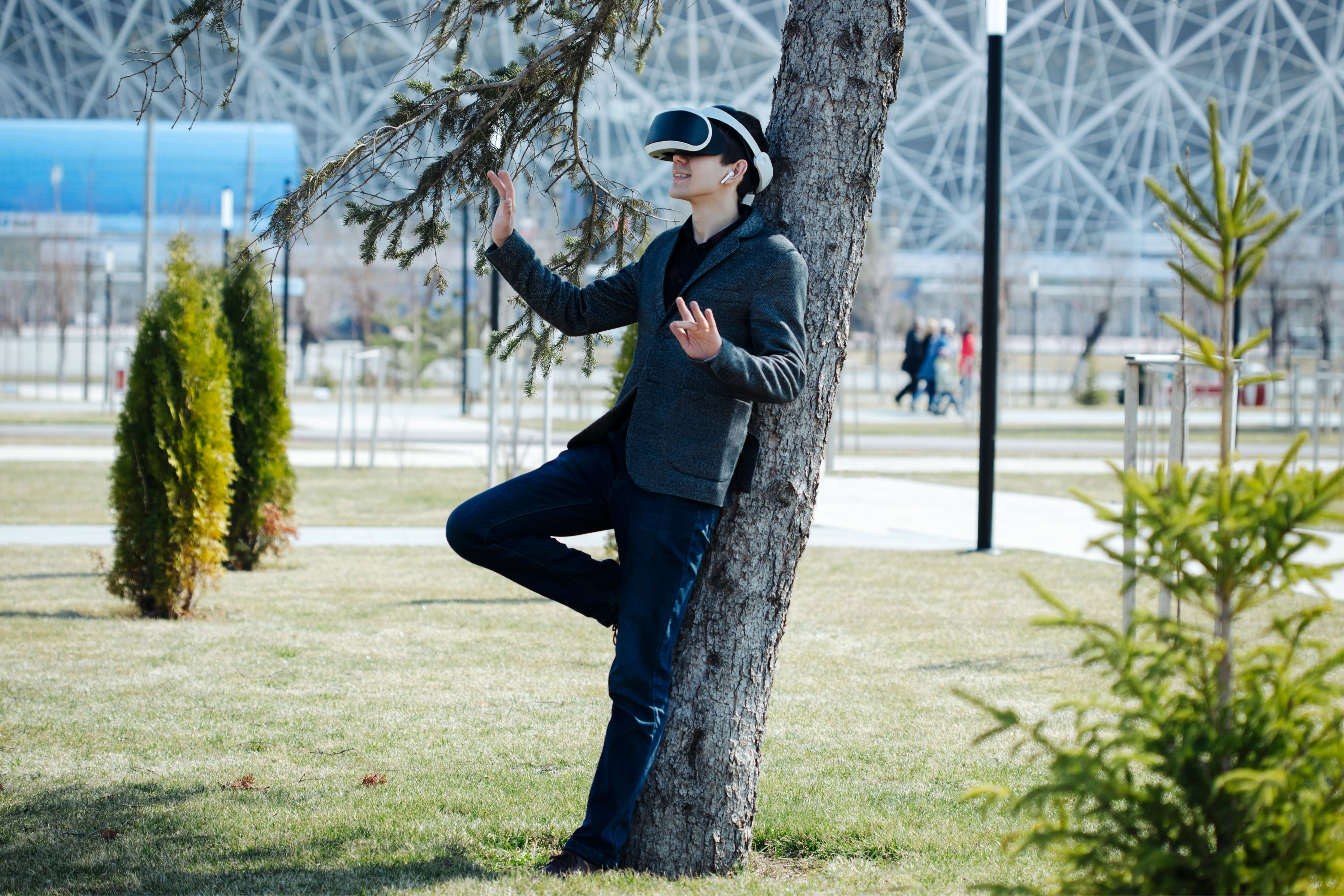 Een jonge man met een virtual reality-bril onderzoekt de omgeving in een park.