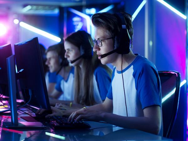 Jongeren met koptelefoons spelen games op computer