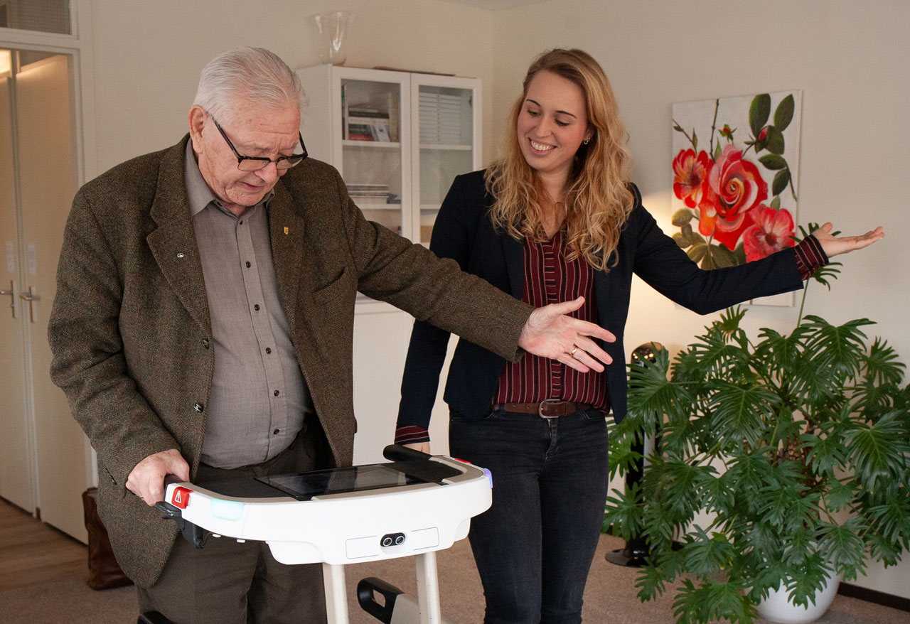 Studente begeleidt oudere man met rollator