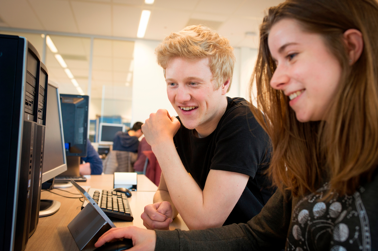 Twee studenten zitten achter een pc