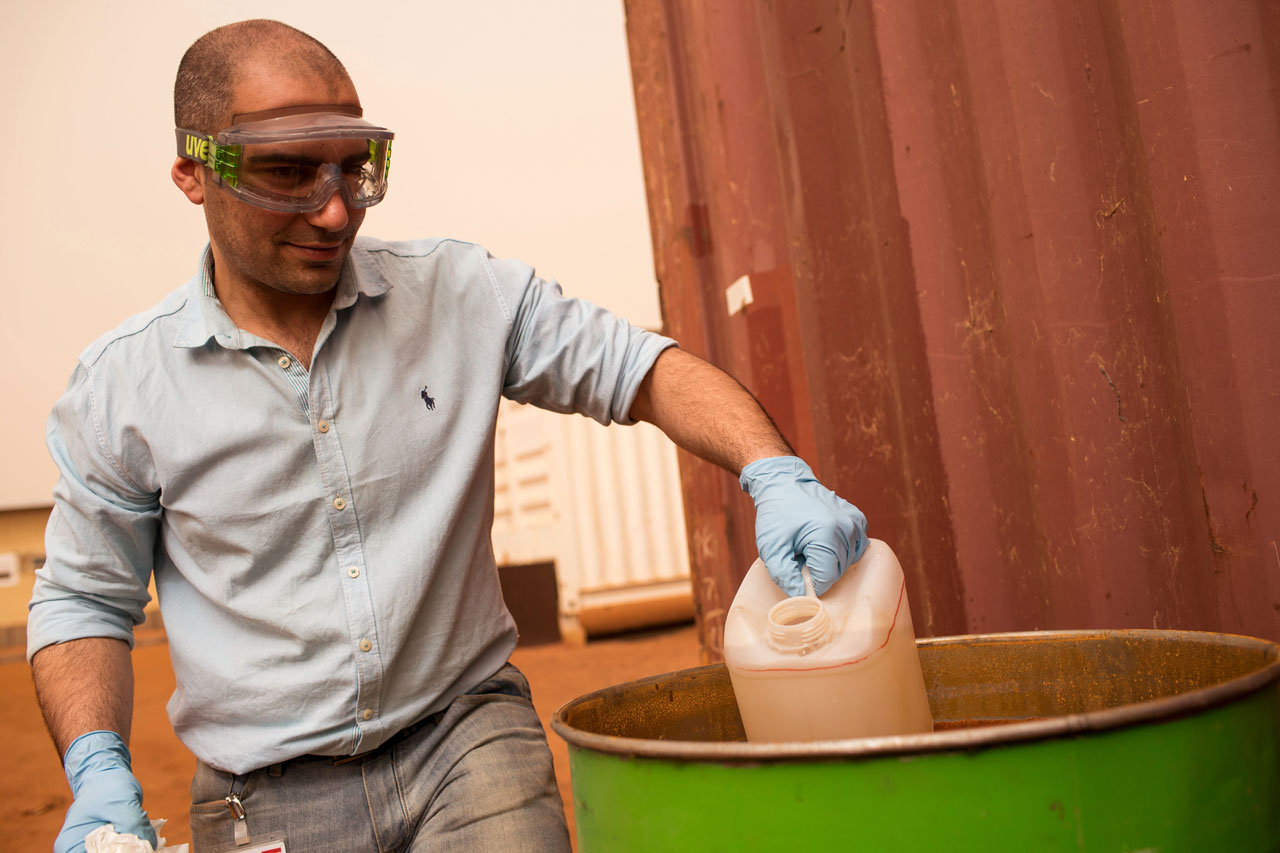 Student met beschermbril haalt jerrycan uit grote ton