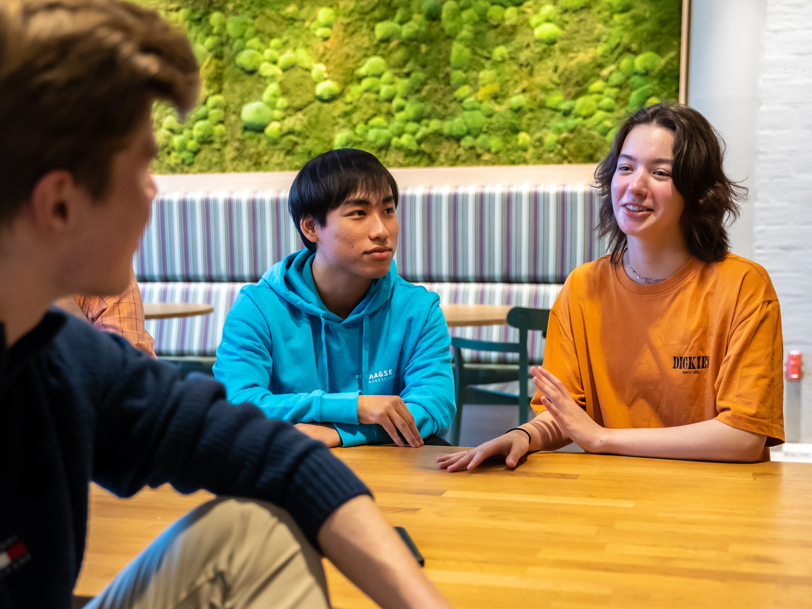 Drie studenten in gesprek aan tafel