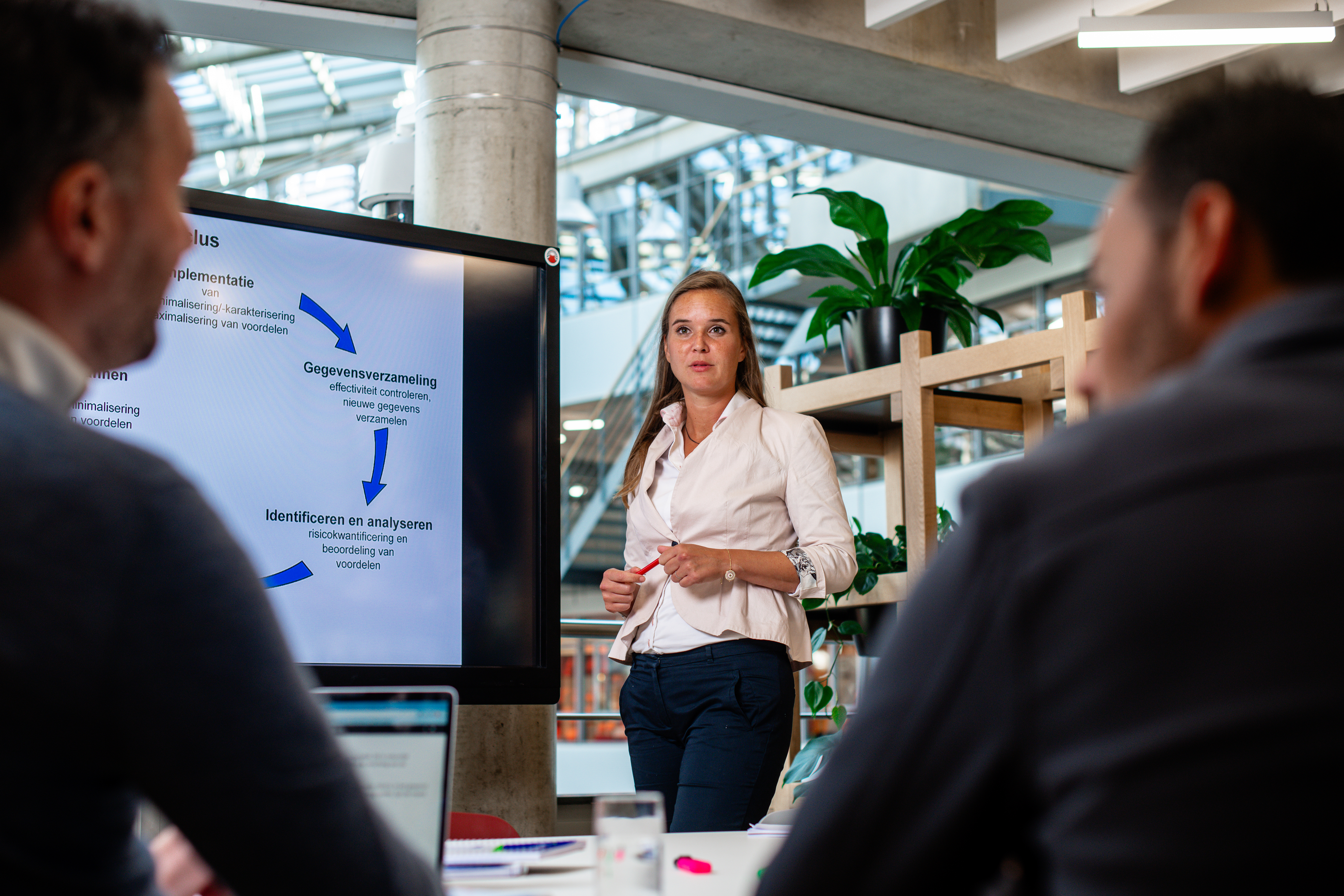 A female presenting to two male students in west75 cafe at the hague university of applied science