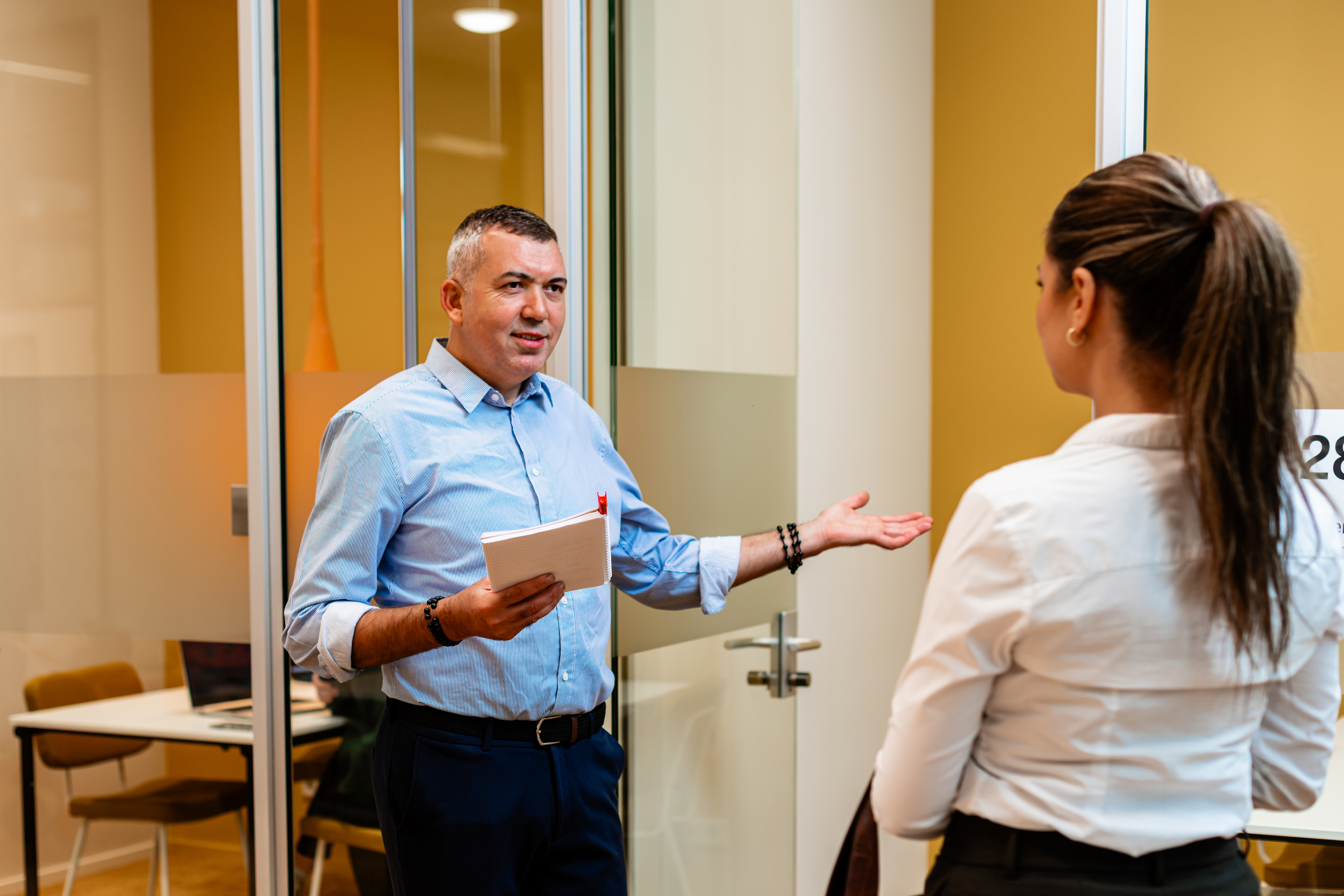 a Male and Female talking in a halway on their way to a meetingroom