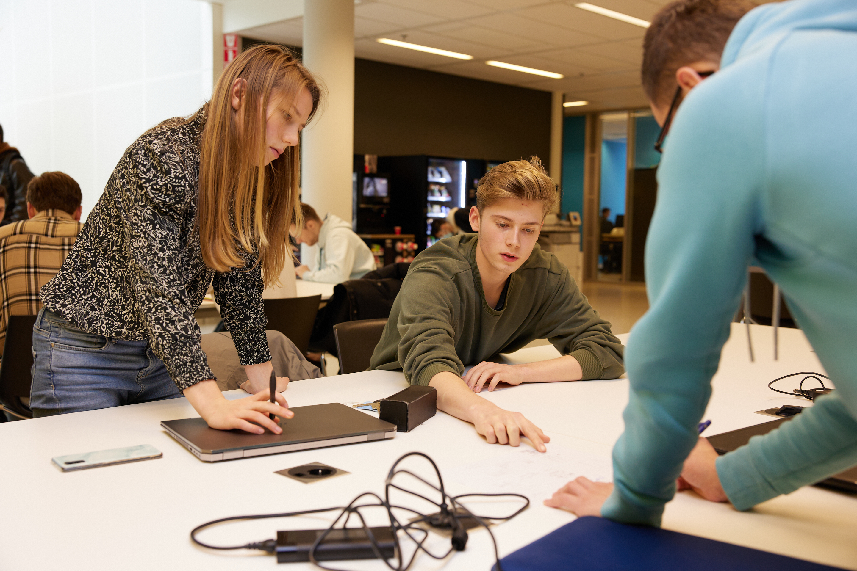 Drie studenten zijn aan het werk aan een tafel