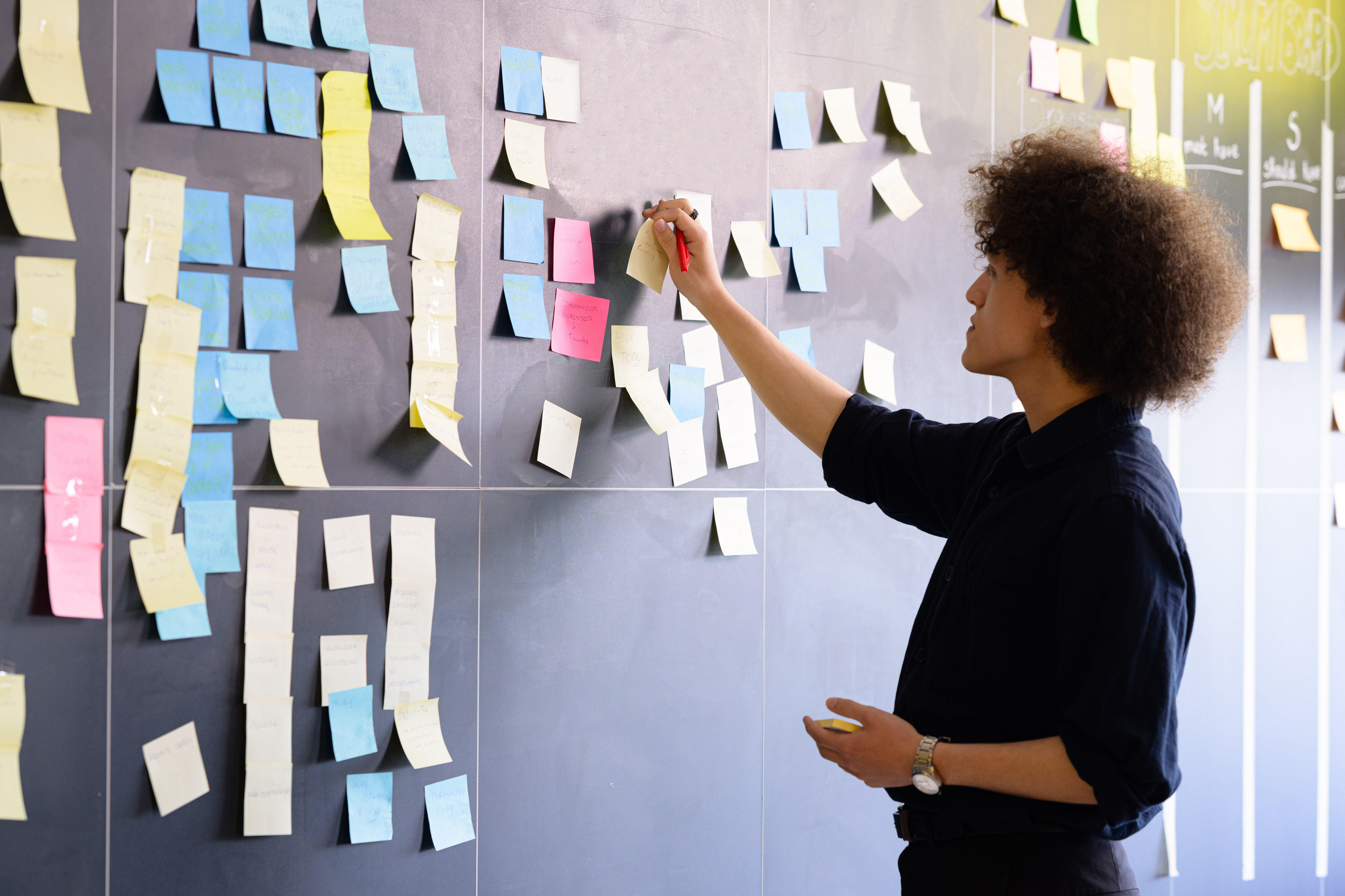 Student plakt een post-it op het krijtbord