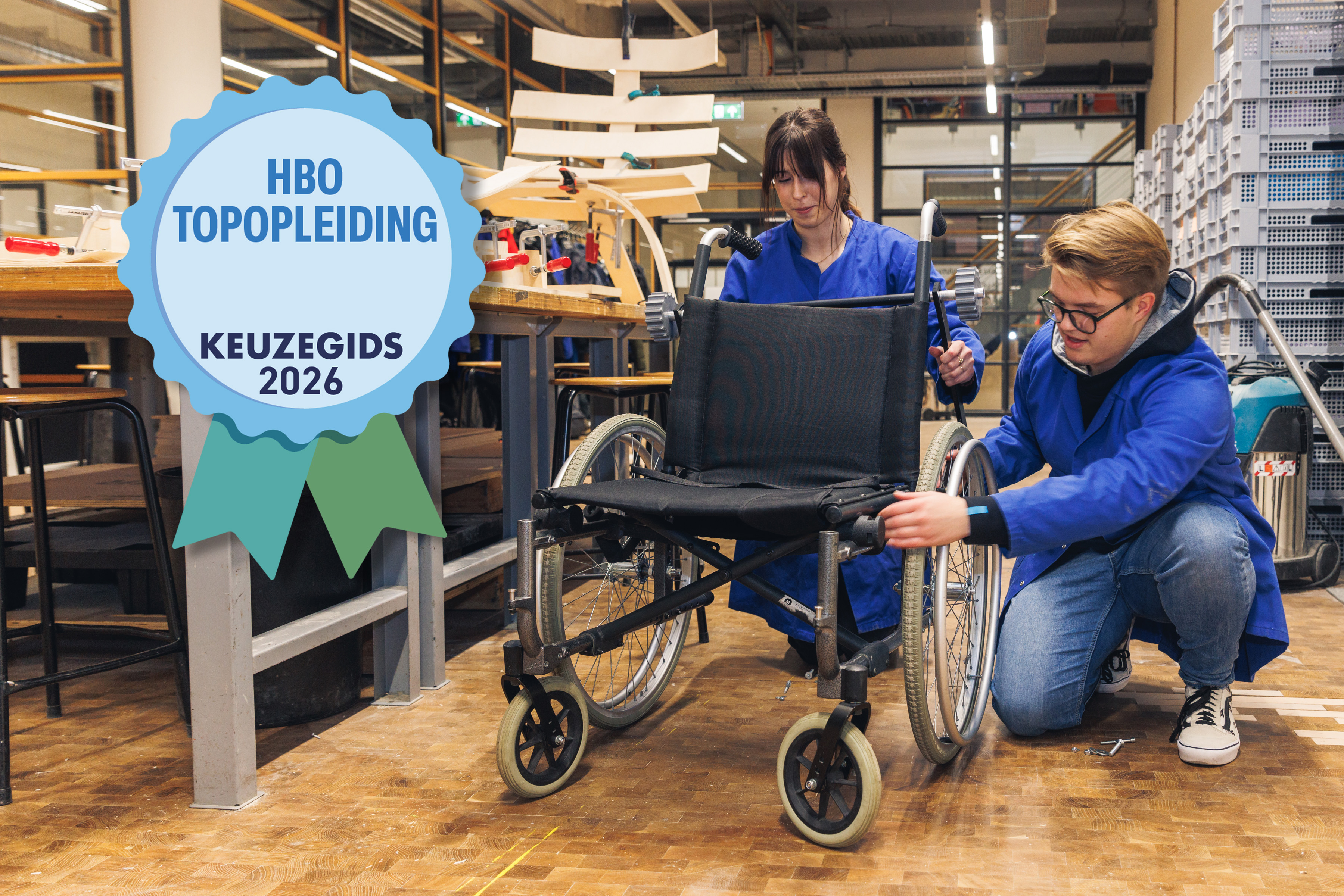 Twee studenten in een werkplaats sleutelen aan een rolstoel; op de voorgrond staat een keurmerk met “HBO Topopleiding Keuzegids 2026”.