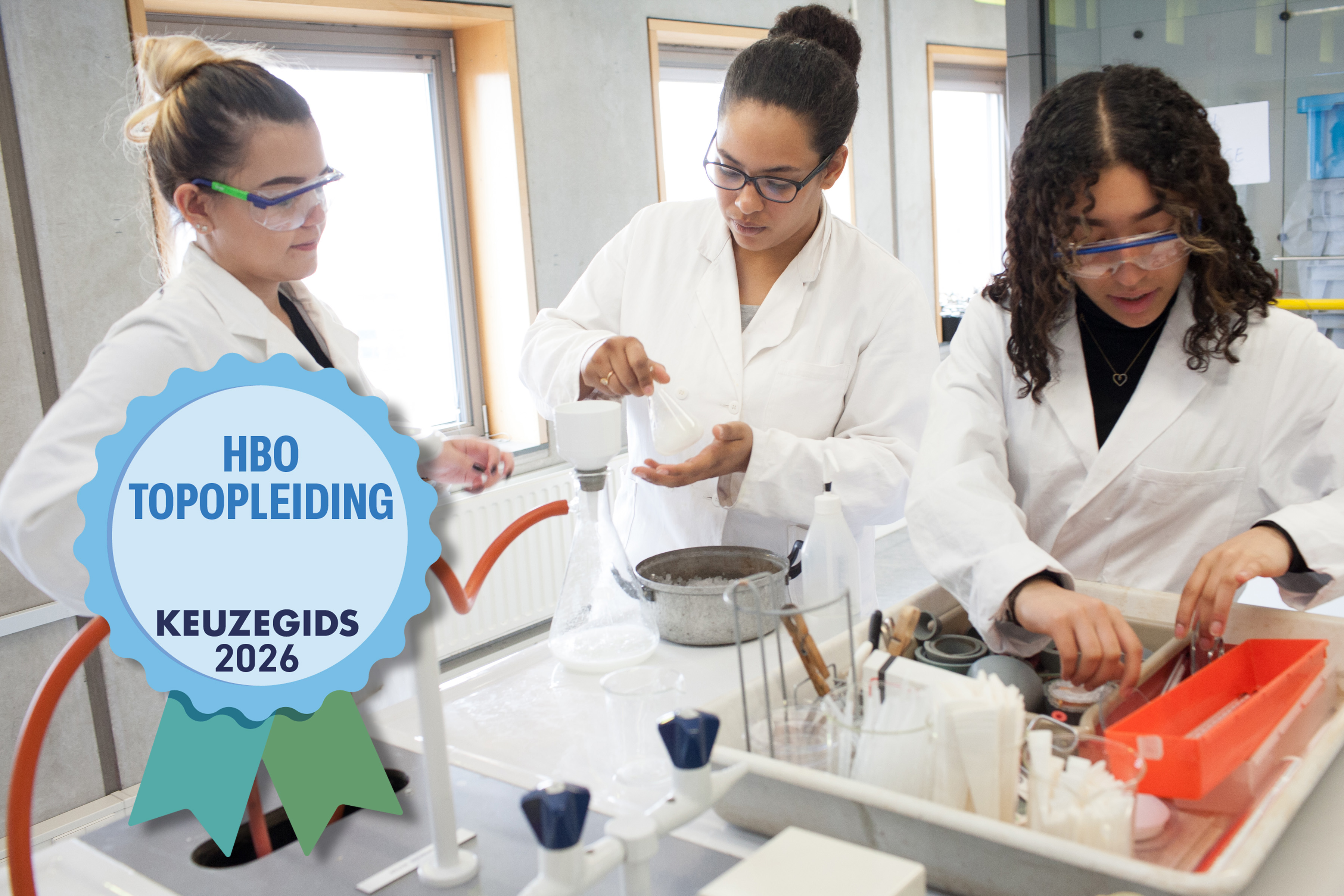 Drie studenten in labjassen werken met laboratoriumapparatuur; op de voorgrond een embleem met "HBO Topopleiding Keuzegids 2026".