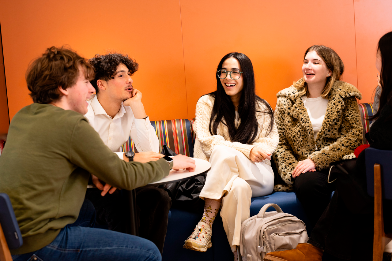 Groep studenten praat met elkaar in vrolijke sfeer
