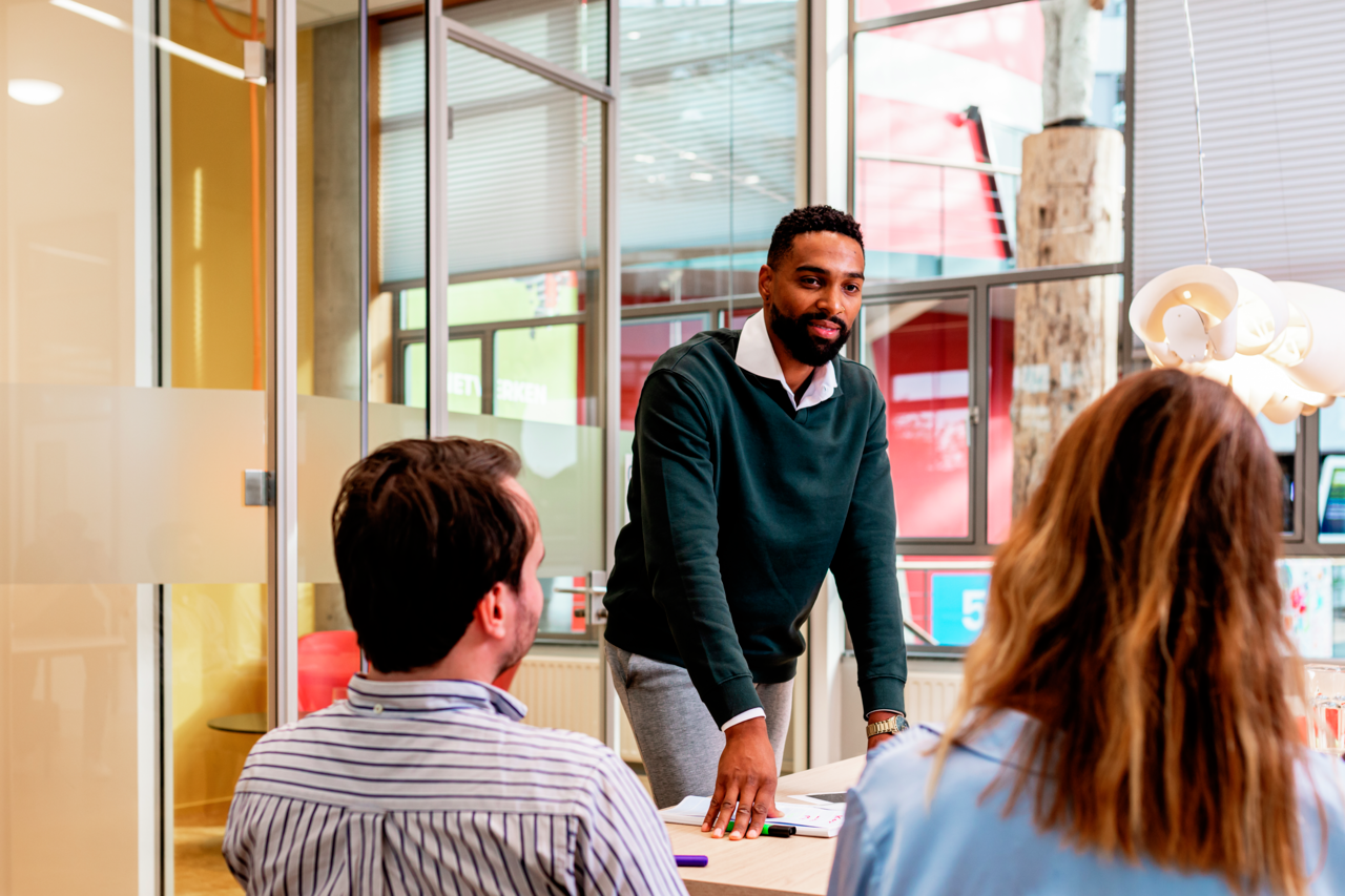 Drie personen aan tafel in gesprek