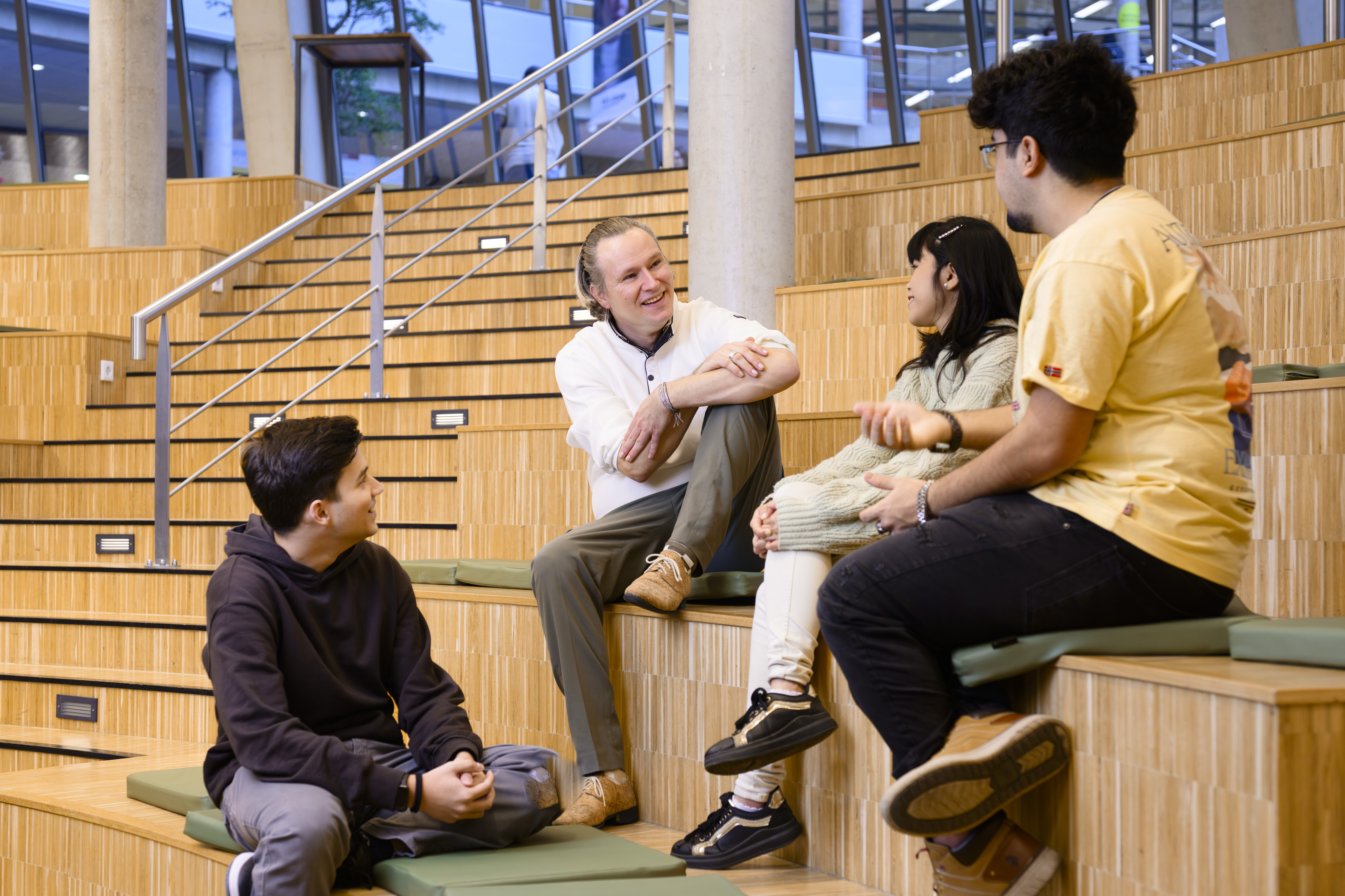 Vier personen zitten samen op een trap te lachen