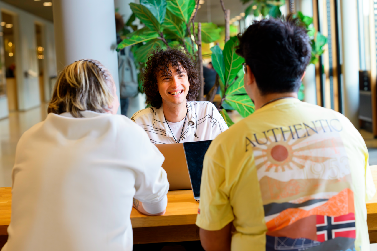 Drie studenten lachend aan tafel