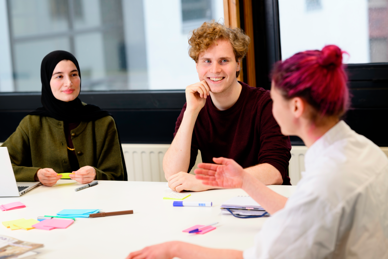 Drie studenten lachend aan tafel