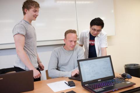 Drie studenten overleggen achter laptop